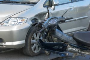 A moped that has been struck by a car. 