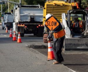 Highway construction worker putting warning signs.