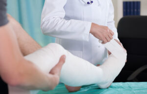 Doctor dressing the injured leg of patient.