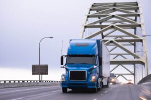 Blue truck trailer passing the bridge.