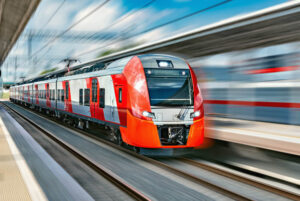 Modern high-speed red train moves fast along the platform.