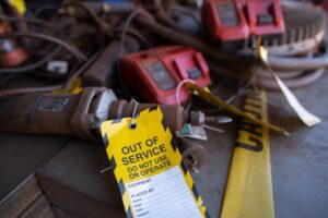 Safety workplaces yellow out of service tag attached on faulty damage metal die grinder power tools construction site.