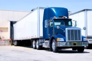 Blue and white tractor trailer truck passing.