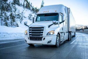 White big rig truck passing in snowy road.