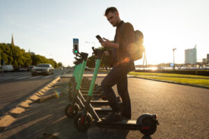 Young man unlocks an e-scooter with his mobile phone.