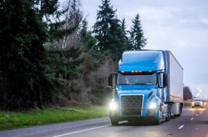 Blue semi-truck passing along the country road.